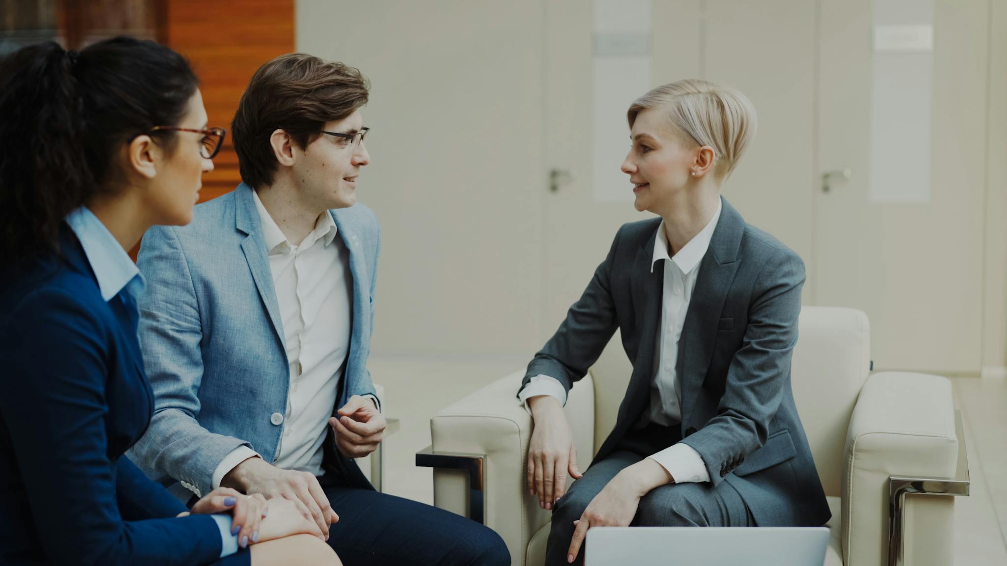 Three professionals engaging in a conversation during a business meeting indoors.